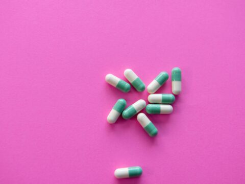white and blue medication pill on pink textile